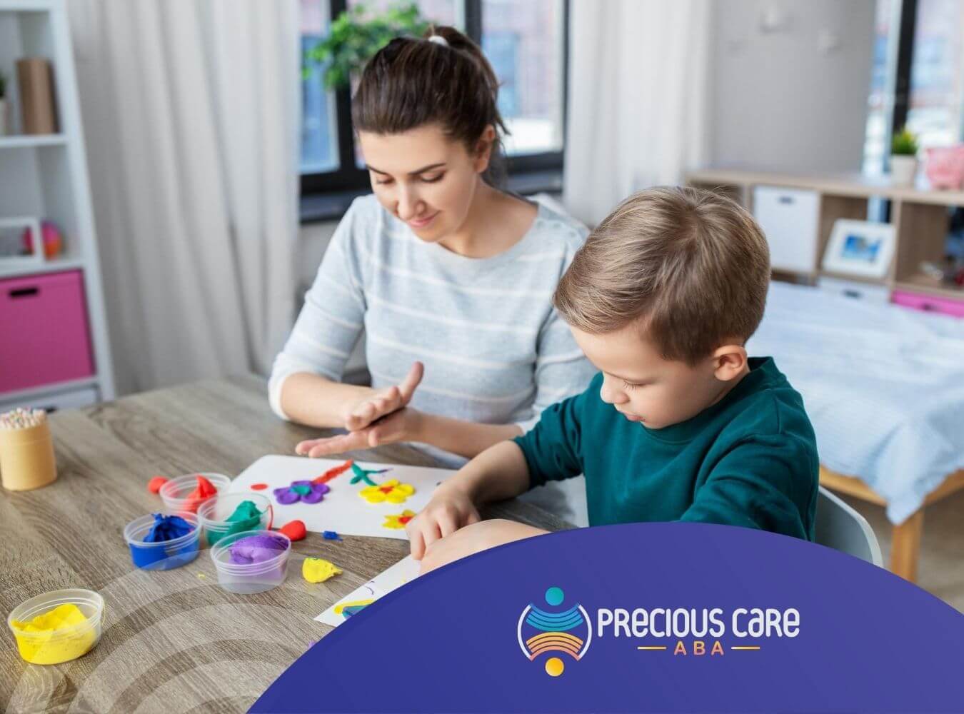 An ABA therapist and autistic boy playing with clay at a table in ABA therapy.