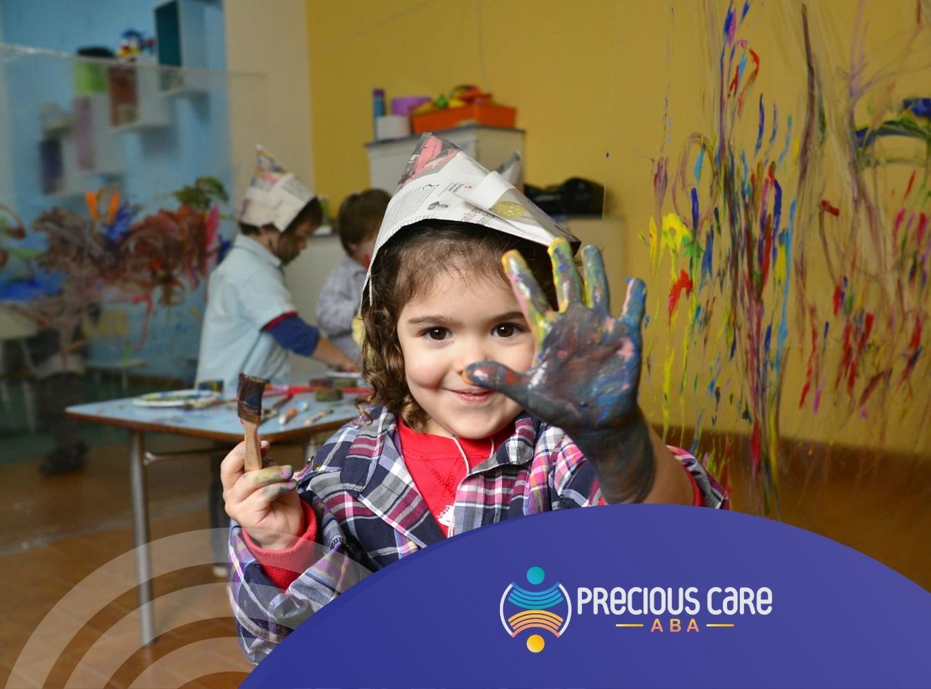 Autistic girl in a classroom, smiling and showing her painted hand during ABA therapy in Maryland.
