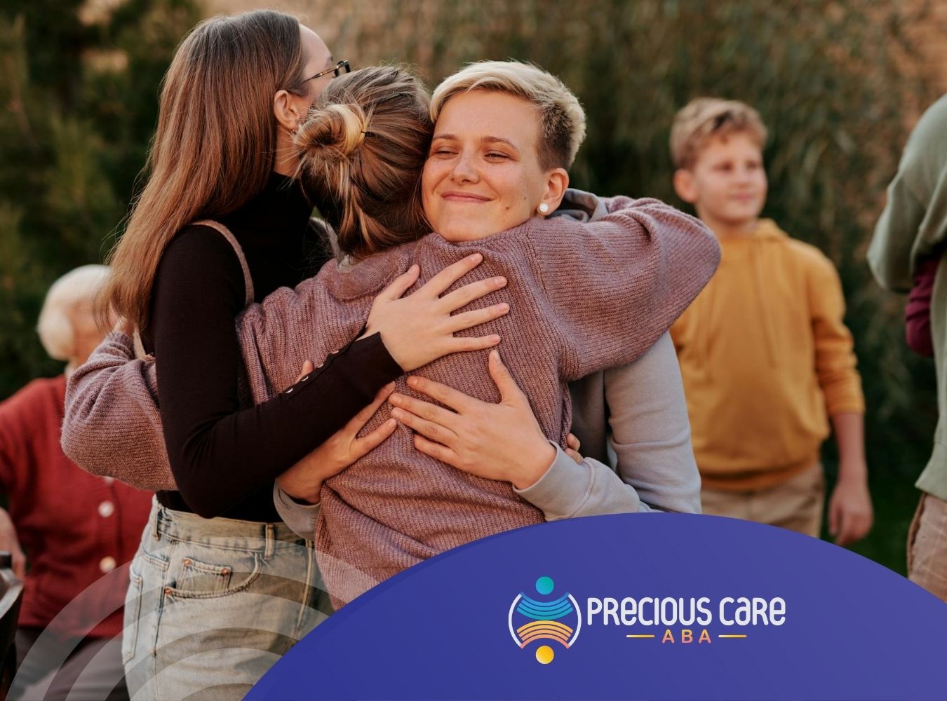 Autistic friends hugging outdoors, surrounded by an autism support group at a gathering in Colorado.