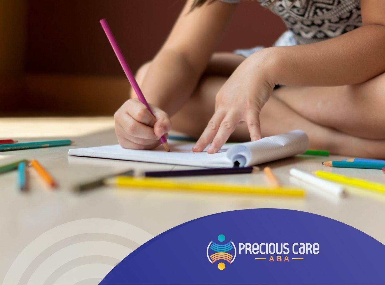 Autistic child sitting on the floor, drawing on paper surrounded by scattered colored pencils in MD.