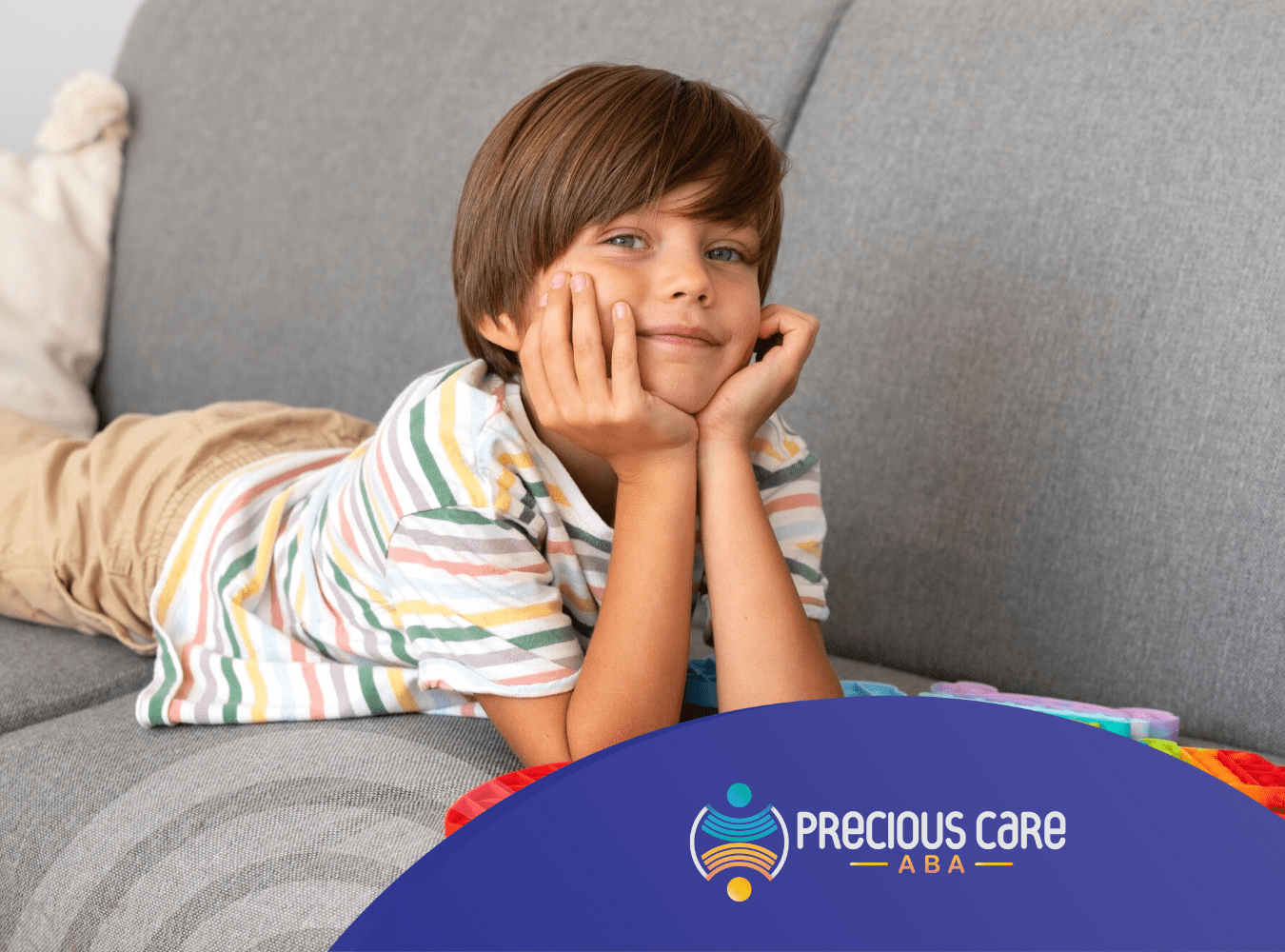 A child with autism lying on a couch playing with fidget toys