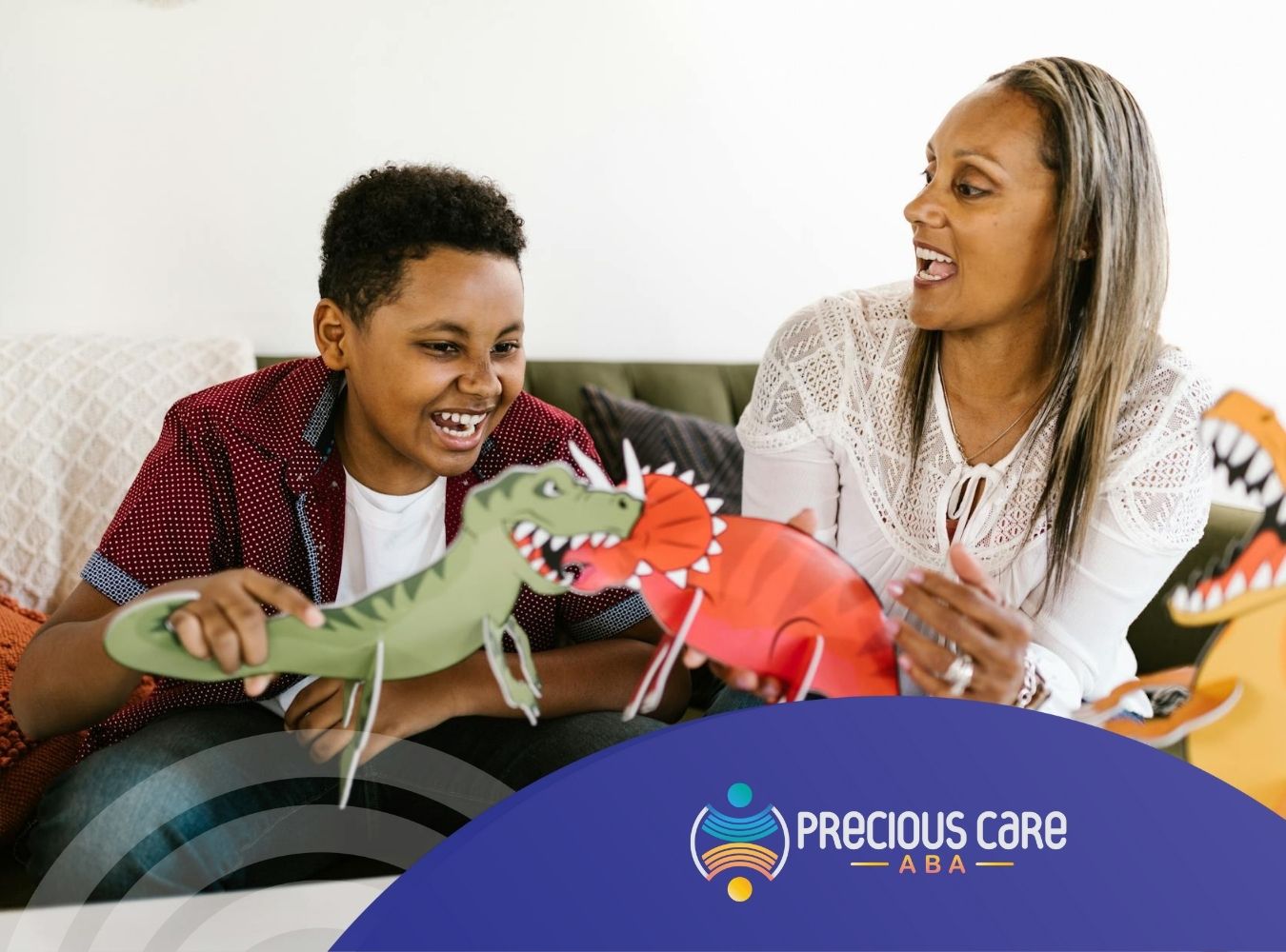 ABA therapist and autistic teen playing with paper dinosaur cutouts, laughing together in Colorado.