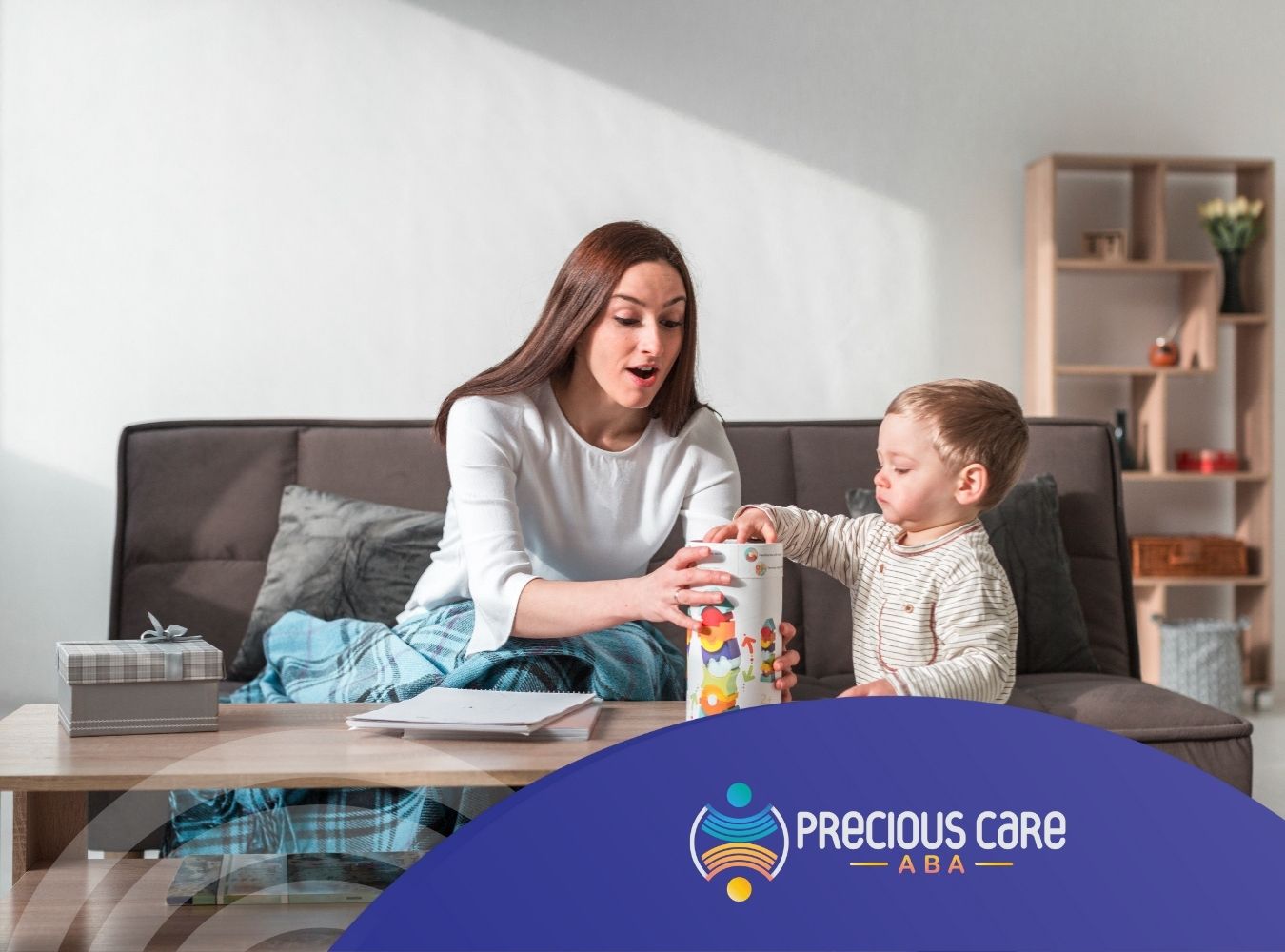 ABA therapist and toddler playing with a toy container at a coffee table.