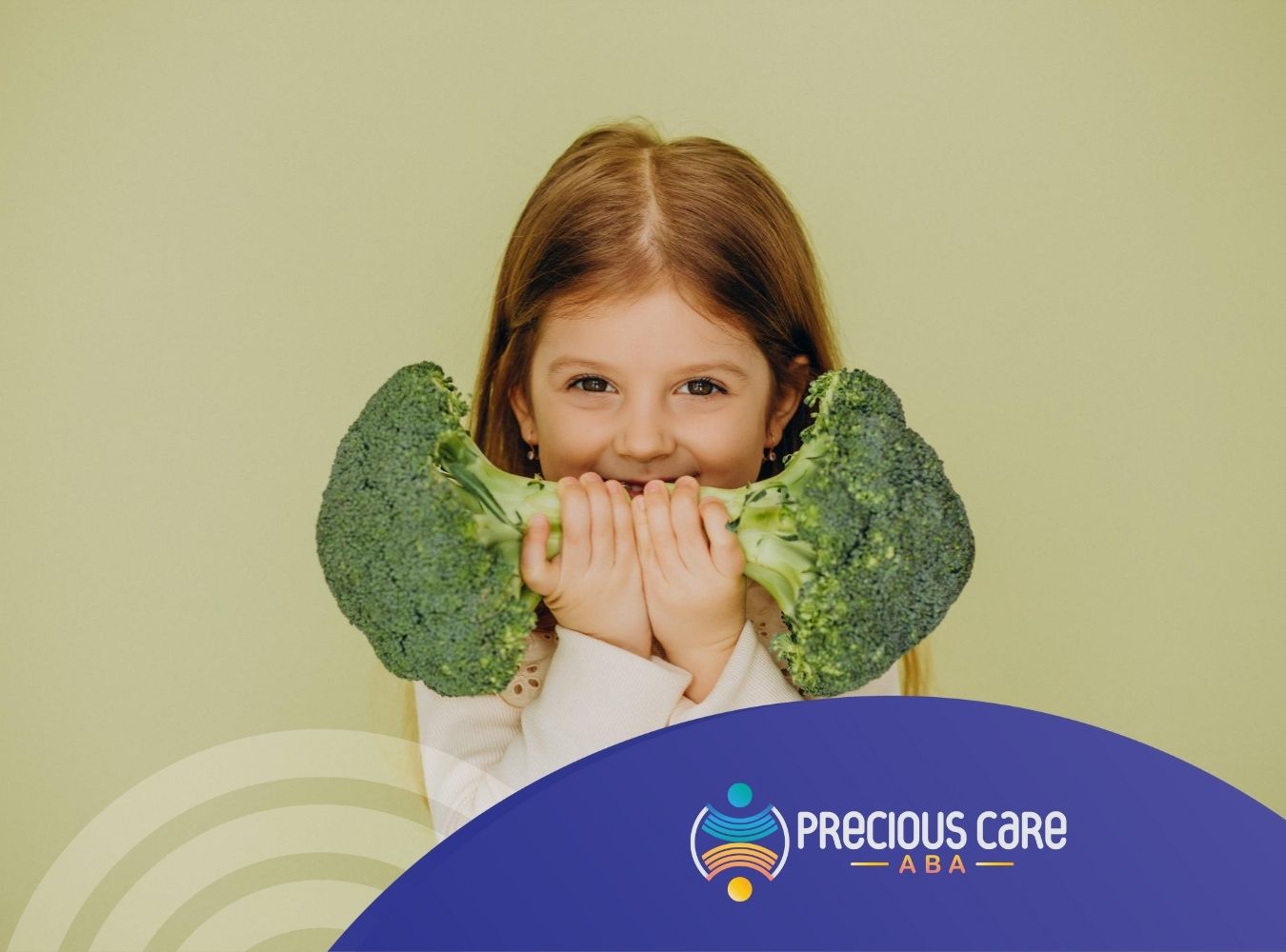 A smiling girl holding two large pieces of broccoli in front of her face.