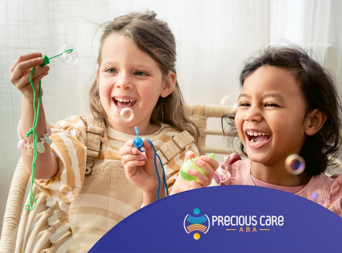 Two autistic girls widely laughing while playing with bubble wands at home indoors in Colorado.