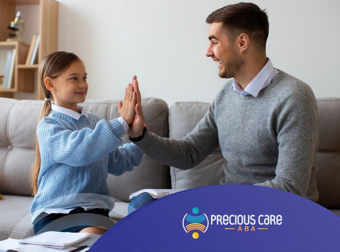 Smiling child and BCBA giving a high five while sitting on a couch.