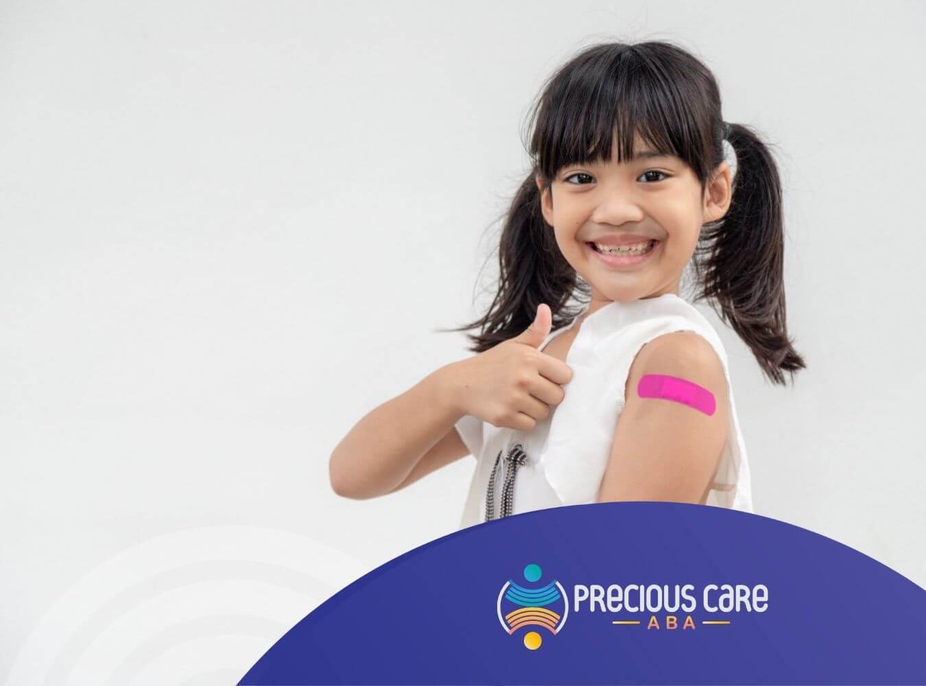 Smiling girl giving a thumbs up, showing a pink bandage on her upper arm after vaccination.