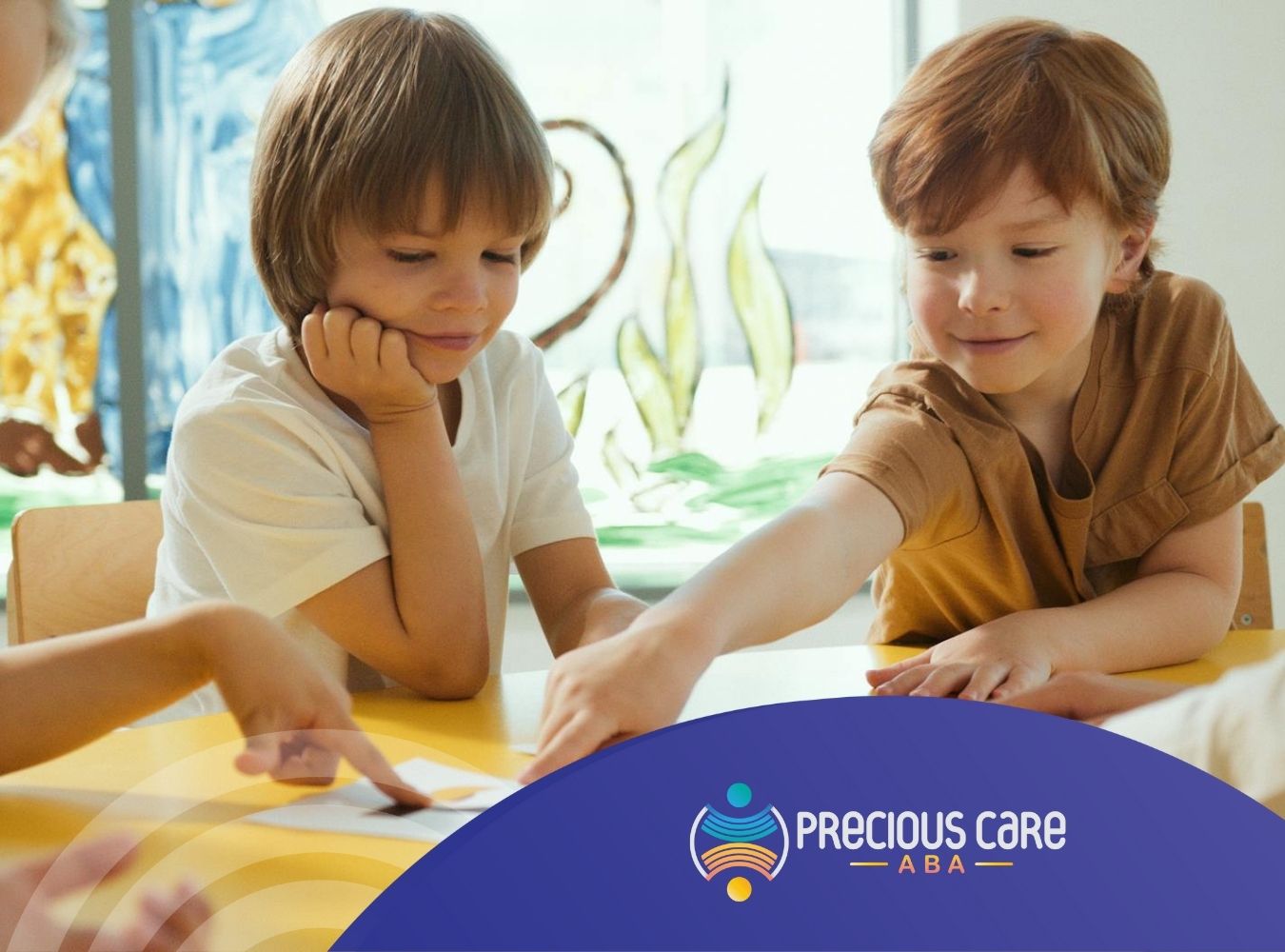 Autistic children pointing at cards on a table during ABA therapy at a classroom in Maryland.